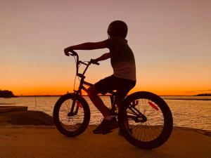 eine Person, die bei Sonnenuntergang am Strand Fahrrad fährt in der Unterkunft Tranquil holiday home on the water’s edge. in Rainbow Beach