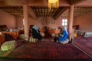 duas mulheres sentadas numa sala com uma mesa em Erg Chegaga Desert Standard Camp em Mhamid