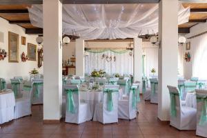 a banquet hall with white tables and green chairs at Kemence Csárda és Szálloda in Nyíregyháza