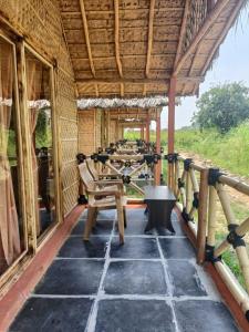 een veranda van een hut met tafels en stoelen bij Rasta Cafe Hmpi in Hampi