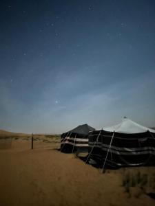 a black and white tent in the desert at night at SandGlass Camp in Bidiyah
