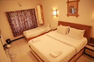 een hotelkamer met 2 bedden en een raam bij The Woodlands Residency- Unmarried and stag groups not allowed in Ooty