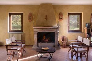 a living room with a fireplace with chairs and a table at Casale Pomodoro in Manziana