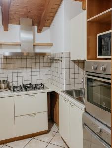 een keuken met witte kasten en een wastafel bij Mansarda de Legn in Cannobio