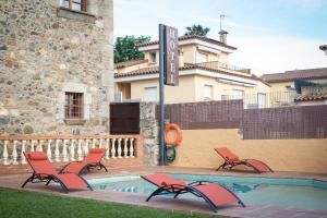 a swimming pool with chairs and a building at Hotel Mas 1670 - Adults Only in Calonge