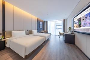 a hotel room with two beds and a flat screen tv at Atour Hotel Guangzhou Panyu Wanbo CBD Hanxi Changlong in Guangzhou