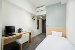a bedroom with a bed and a desk with a television at KOKO HOTEL Kagoshima Tenmonkan in Kagoshima