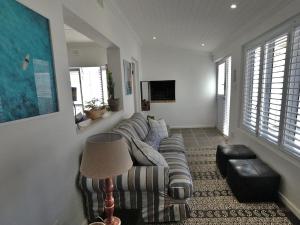 ein Wohnzimmer mit Sofa und Fernseher in der Unterkunft Sun Kiss Beach and Deluxe Garden Cottages in Kapstadt