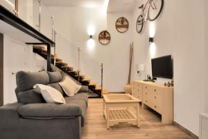 sala de estar con sofá, TV y escaleras en Moderno loft en el corazón histórico de Estepona - CASA PEPITA 17, en Estepona