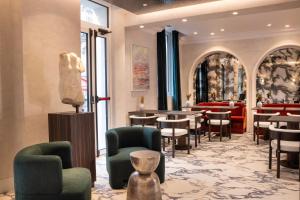 a restaurant with chairs and tables and a statue at Hotel des Carmes by Malone in Paris