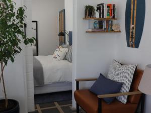 ein Wohnzimmer mit einem Bett, einem Stuhl und einer Pflanze in der Unterkunft Sun Kiss Beach and Deluxe Garden Cottages in Kapstadt
