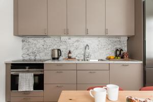 a kitchen with white cabinets and a wooden table at Modern New Stylish Apartment in Åkersberga