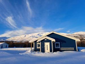 特羅姆瑟的住宿－Elvenes, krypinn for to，雪中蓝色的房子,有雪覆盖的山