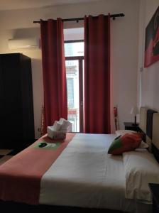 a bedroom with a bed with red curtains and a window at Hotel Plebiscito Aparthotel in Naples