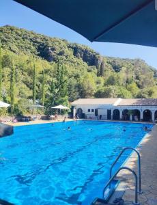 a swimming pool with blue water in front of a mountain at Aptm Dayma Sierra junto al río Majaceite. in Benamahoma