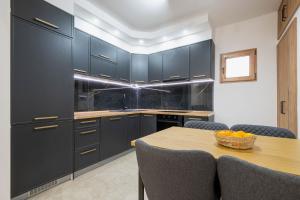 een keuken met donkerblauwe kasten en een houten tafel bij Filip in Bar