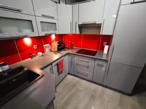 a kitchen with red walls and white cabinets at Mieszkanie Tarnowo Podgórne in Tarnowo Podgórne