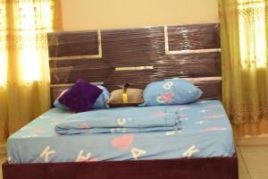 a bed with a wooden headboard and some pillows at Royal Suites and Apartments in Jidu