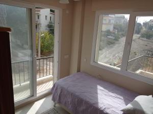a bedroom with two large windows and a bed in it at Seferihisar Akarca Denize 130 metre uzaklıkta in Seferihisar