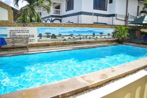 a large blue swimming pool in front of a building at Pendo Villas Diani Beach in Diani Beach