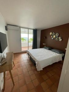 Schlafzimmer mit einem Bett, einem Schreibtisch und einem Fenster in der Unterkunft TI BONHEUR DE TARTANE in La Trinité