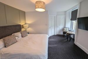 um quarto com uma cama branca e uma televisão em The White Hart Inn, Hawes em Hawes