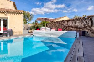 een zwembad met rode stoelen en een parasol naast een huis bij Villa Farigoule in Lunel