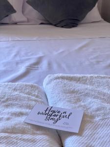 a sign sitting on a bed with white sheets at Casa Olivia in Coron