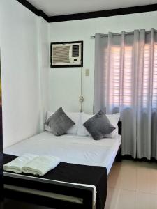 a bedroom with a bed with white walls and a window at Casa Olivia in Coron