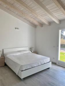 a white bedroom with a bed and a large window at Villetta 2 La Caletta in La Caletta