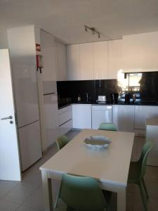 uma cozinha com uma mesa branca e cadeiras verdes em House with amazing beach view! em Carvoeiro