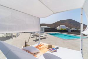 a patio with a swimming pool and a white umbrella at Vv Villa Secretos de Yaiza 1 by Hh - private pool & BBQ in Yaiza