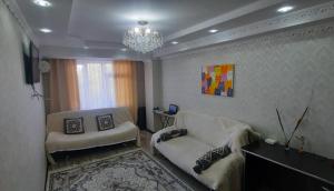 a living room with a couch and a chandelier at Однокомнатная квартира, Новая! in Mayevka