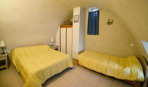 duas camas num quarto com lençóis amarelos em Gîte le Four d'Odilon em La Malène