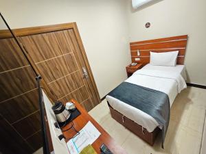 1 dormitorio con 1 cama y puerta de madera en Villa Hotel Basra, en Basora
