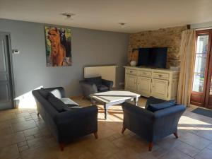 a living room with couches and a table and a tv at Alpagas de Barres in Sénaillac-Latronquière