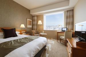a hotel room with a bed and a desk and a television at Hotel Nikko Kanazawa in Kanazawa
