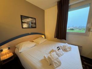 a bedroom with a bed with white sheets and a window at Le 2 by Hotel Akena - Nantes Beaujoire, Porte de Sainte Luce in Sainte-Luce-sur-Loire