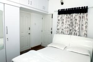 - une chambre avec un lit blanc et un rideau dans l'établissement HAILSTONE HOME STAY, à Ooty