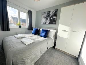 a bedroom with a large bed with blue pillows at No.32 by Blue Skies Stays in Bowburn
