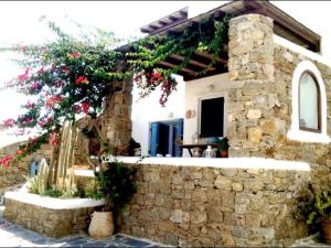 a house with a stone wall and a tree with flowers at Beautiful Traditional Apt in Ano Mera Mikonos in Ano Mera