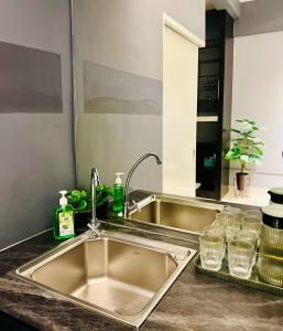 um balcão de cozinha com um lavatório e um espelho em M Suite Homestay, Aeropod Sovo Kota Kinabalu em Tanjong Aru