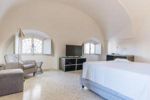 a bedroom with a bed and a chair and a television at Foresteria Il Voltone in Cremona