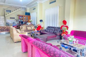 sala de estar con sofás rosados y mesa en RedDoorz Syariah at D'Rizs Homestay en Bukittinggi