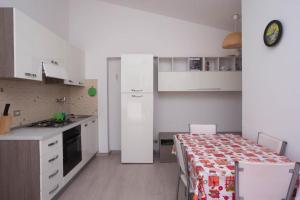 uma cozinha com armários brancos e uma mesa num quarto em M200 - Marcelli, nuovo bilocale a 200mt dal mare em Marcelli