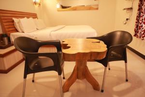 Duas cadeiras e uma mesa de madeira num quarto com uma cama em The Woodlands Residency- Unmarried and stag groups not allowed em Ooty