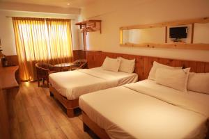 um quarto de hotel com duas camas e uma mesa em The Woodlands Residency- Unmarried and stag groups not allowed em Ooty