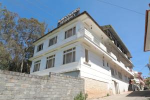 um edifício branco com uma placa em cima em The Woodlands Residency- Unmarried and stag groups not allowed em Ooty