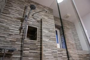 a bathroom with a shower with a brick wall at Dalwhinnie Apartment in Oban