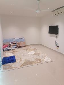 a room with a rug on the floor and a television at الخوض السادسة واحة المعرفة in Al Khawḑ